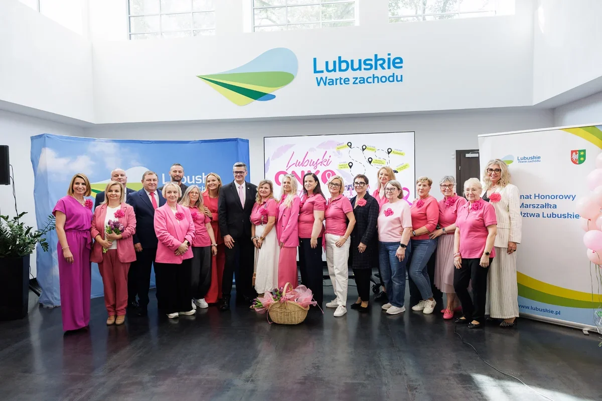 Grupa osób, głównie kobiet ubranych na różowo, pozuje do pamiątkowego zdjęcia podczas wydarzenia promującego Lubuskie.